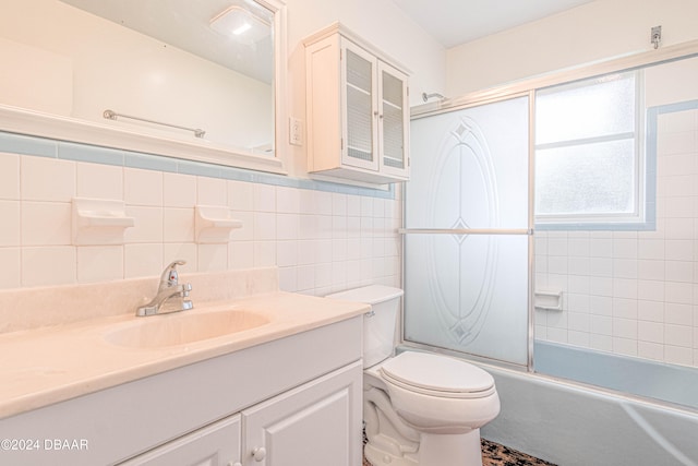 full bathroom featuring enclosed tub / shower combo, vanity, toilet, and tile walls