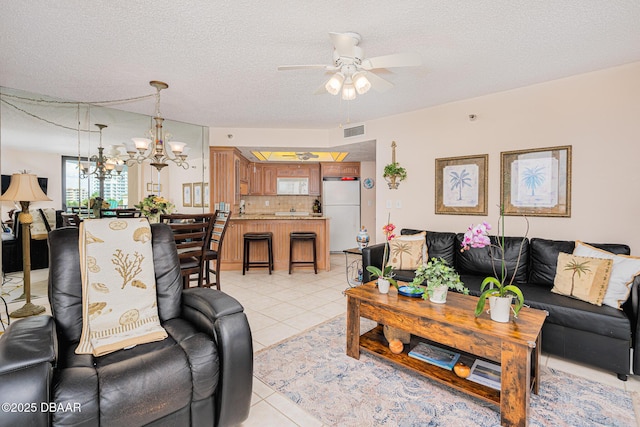 tiled living room with a textured ceiling and ceiling fan with notable chandelier