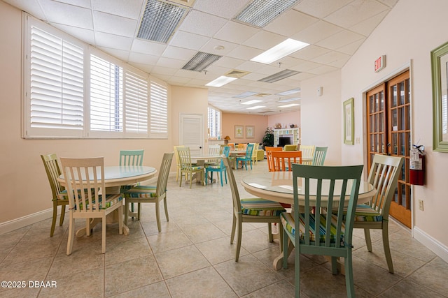 dining area featuring light tile patterned floors and a paneled ceiling