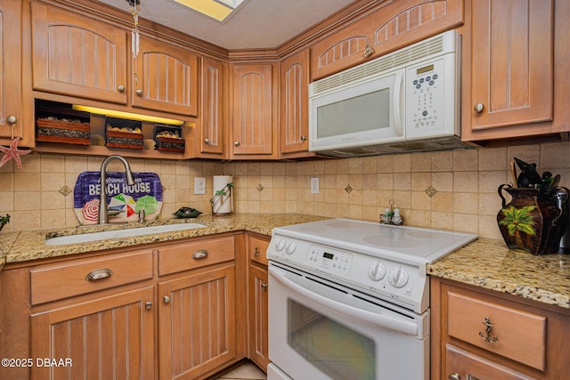 kitchen with decorative backsplash, white appliances, light stone countertops, and sink