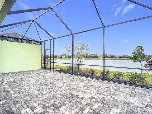 view of patio / terrace featuring glass enclosure and a water view