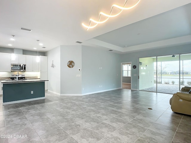 unfurnished living room featuring a raised ceiling and sink