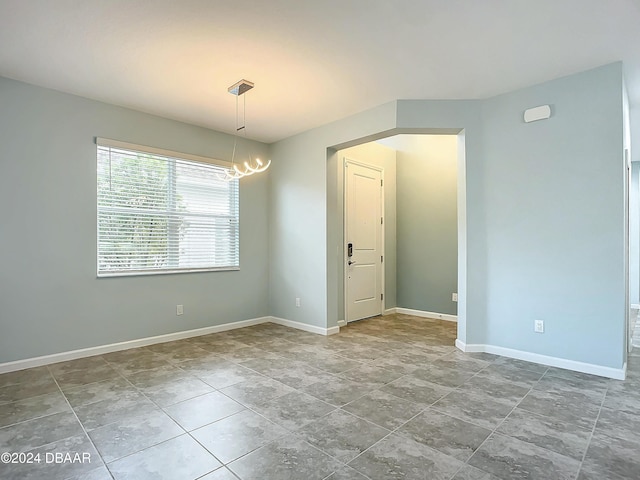 unfurnished room featuring a chandelier