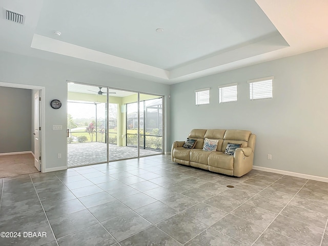 tiled living room featuring a raised ceiling and ceiling fan