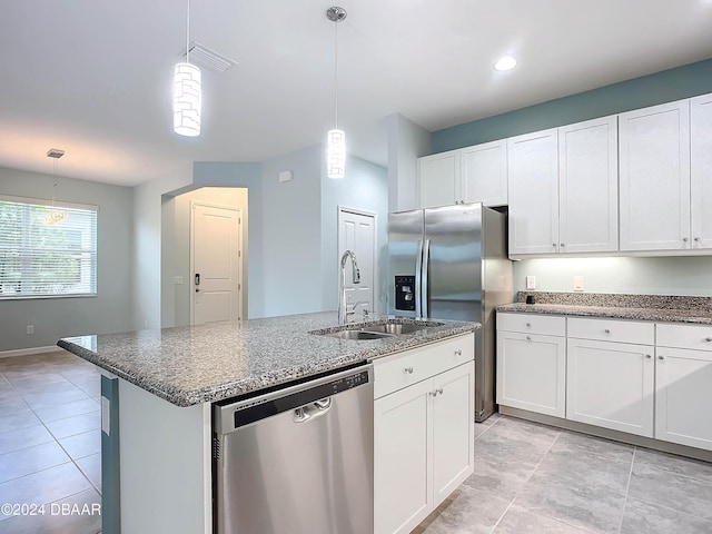 kitchen with white cabinets, appliances with stainless steel finishes, pendant lighting, and an island with sink