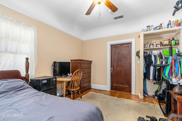 bedroom with visible vents, baseboards, wood finished floors, and a ceiling fan