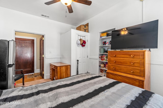 bedroom with visible vents, freestanding refrigerator, and ceiling fan