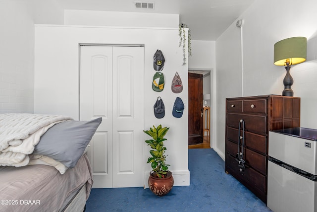 bedroom with dark colored carpet, visible vents, and a closet