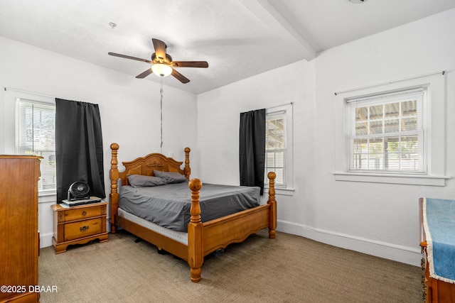 bedroom with baseboards, beam ceiling, light colored carpet, and a ceiling fan