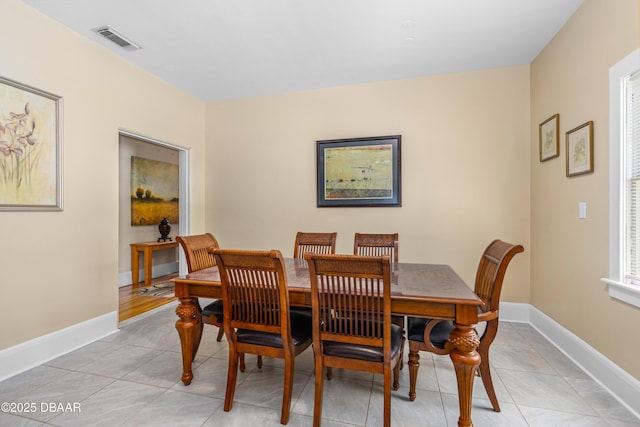 dining room featuring light tile patterned floors, visible vents, and baseboards