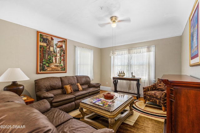 living area with baseboards and a ceiling fan