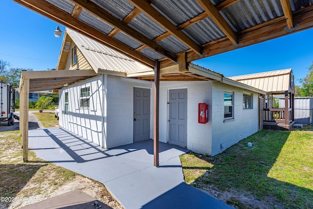 exterior space featuring concrete block siding, a lawn, and metal roof