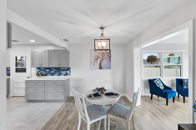 dining area featuring a notable chandelier, a textured ceiling, and light hardwood / wood-style flooring