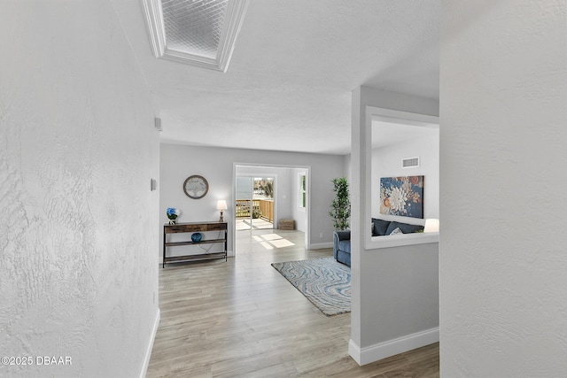 hall with light hardwood / wood-style floors and a textured ceiling