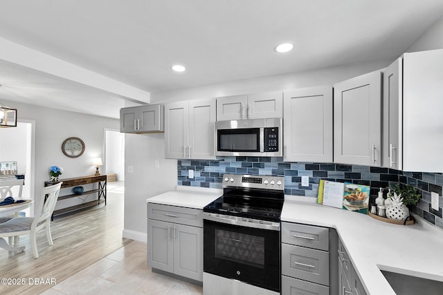 kitchen with tasteful backsplash, stainless steel appliances, and gray cabinetry