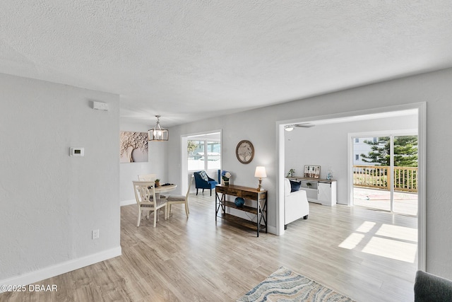 living room featuring an inviting chandelier, light hardwood / wood-style flooring, and a textured ceiling