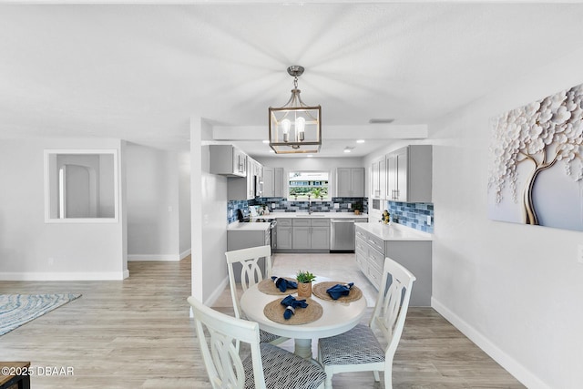 dining room with sink, a chandelier, and light wood-type flooring