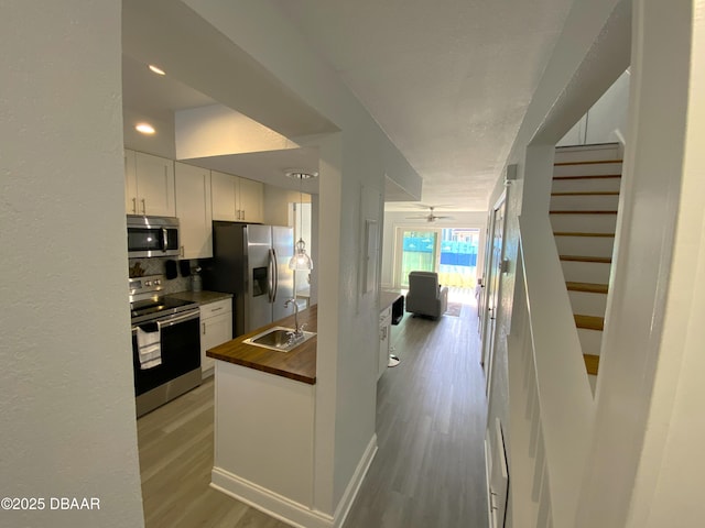 kitchen featuring sink, white cabinetry, wooden counters, stainless steel appliances, and light hardwood / wood-style floors