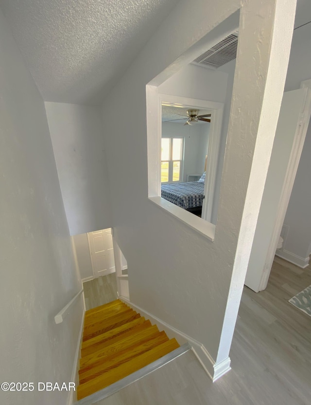 stairs with hardwood / wood-style flooring and a textured ceiling