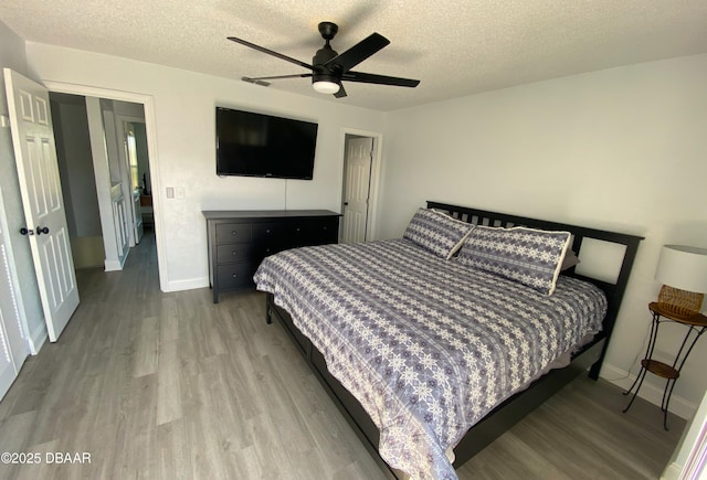 bedroom with ceiling fan, light hardwood / wood-style floors, and a textured ceiling