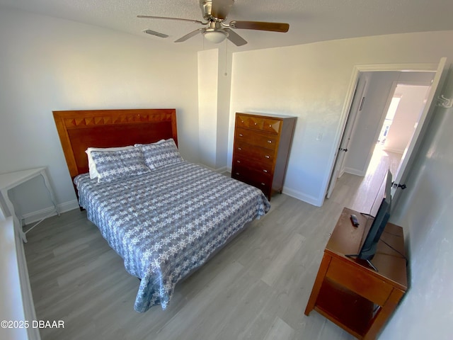 bedroom featuring ceiling fan, a textured ceiling, and light wood-type flooring