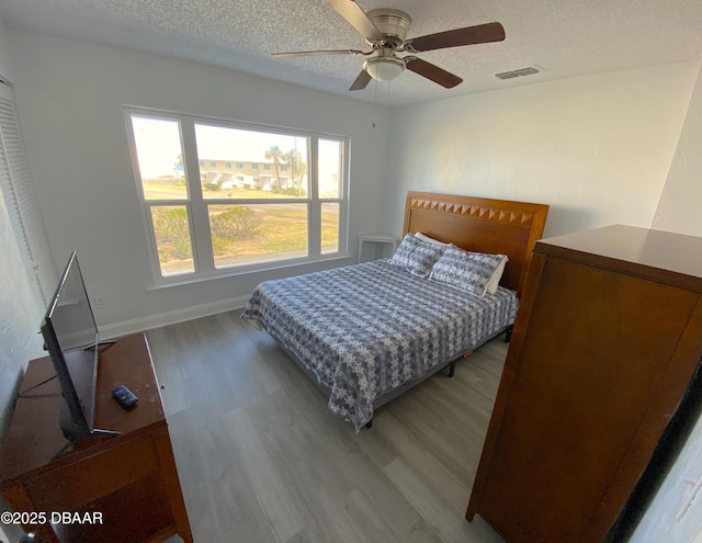 bedroom featuring ceiling fan, hardwood / wood-style floors, and a textured ceiling