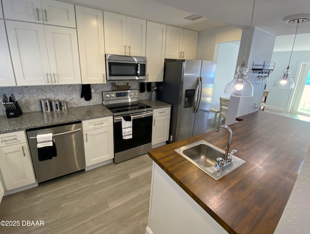 kitchen with hanging light fixtures, sink, white cabinets, and appliances with stainless steel finishes