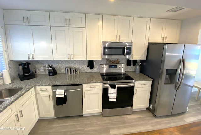 kitchen with appliances with stainless steel finishes, white cabinets, and light hardwood / wood-style floors