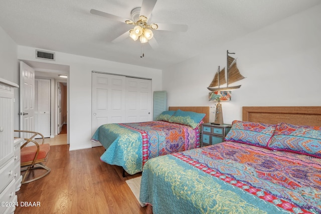 bedroom with ceiling fan, wood-type flooring, a textured ceiling, and a closet