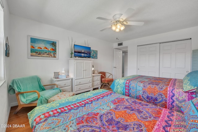 bedroom featuring hardwood / wood-style floors, a textured ceiling, a closet, and ceiling fan