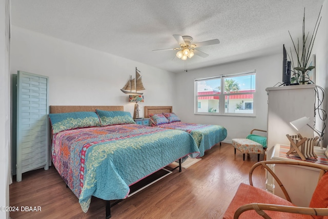 bedroom with a textured ceiling, ceiling fan, and dark wood-type flooring