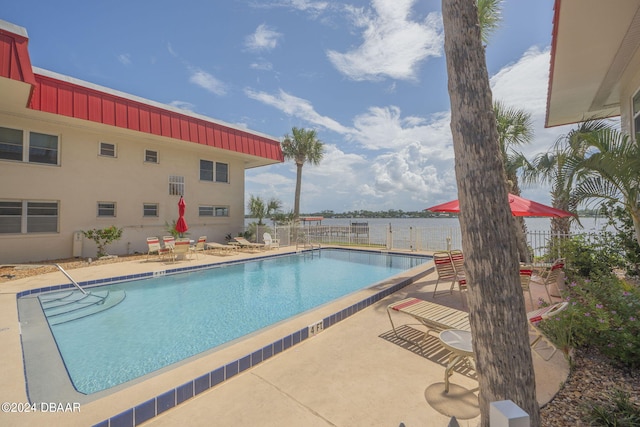 view of swimming pool featuring a patio area and a water view