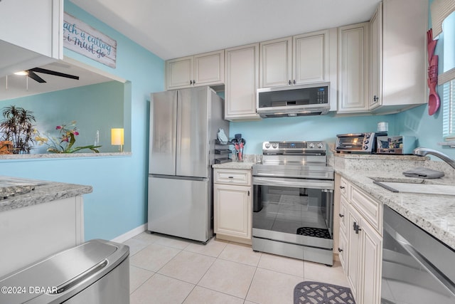 2901 N Halifax Ave Unit 218, Daytona Beach, FL 32118 - kitchen with stainless steel appliances, a ceiling fan, light tile patterned flooring, cream cabinetry, and light stone countertops