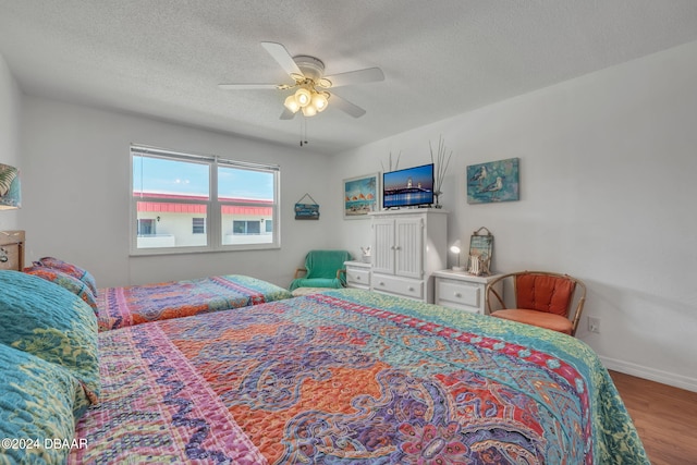 bedroom featuring ceiling fan, wood-type flooring, and a textured ceiling