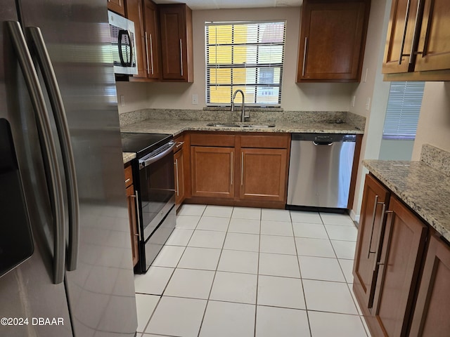 kitchen featuring light tile patterned floors, appliances with stainless steel finishes, sink, and light stone countertops