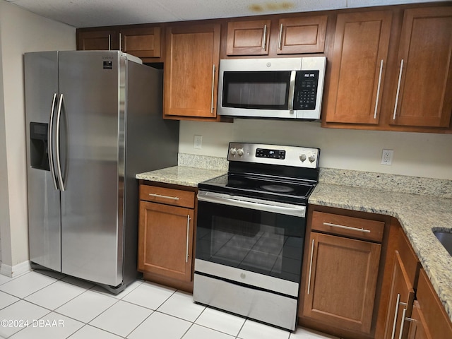 kitchen featuring light stone countertops, light tile patterned floors, and appliances with stainless steel finishes