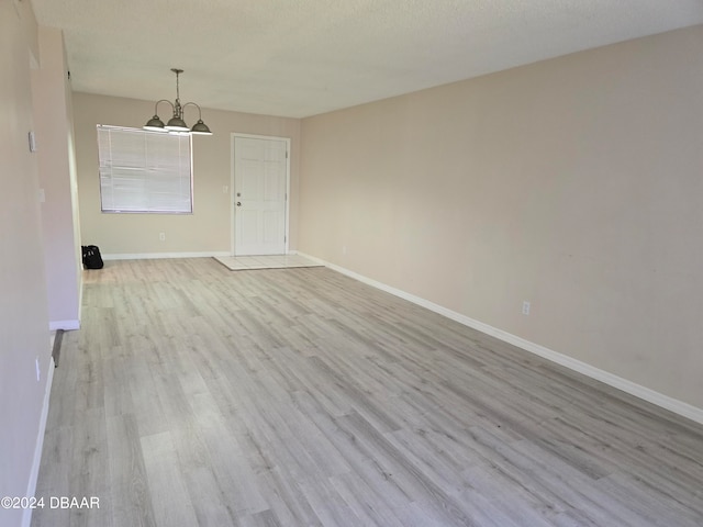 unfurnished room featuring light hardwood / wood-style floors and a textured ceiling