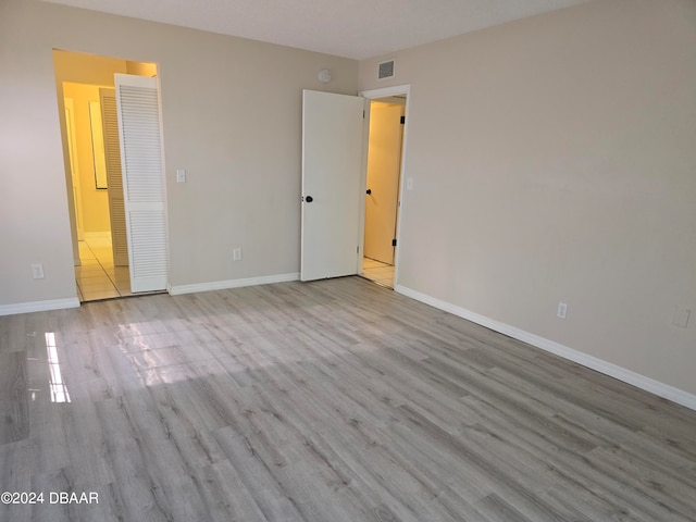 unfurnished bedroom featuring light wood-type flooring and ensuite bathroom