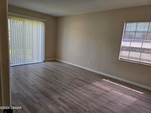 empty room with a textured ceiling and dark hardwood / wood-style floors