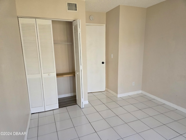 unfurnished bedroom featuring light tile patterned floors, a textured ceiling, and a closet