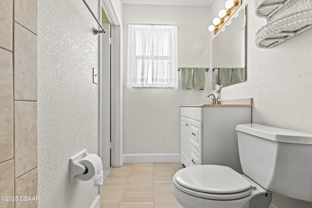 full bathroom with tile patterned floors, toilet, baseboards, vanity, and a textured wall