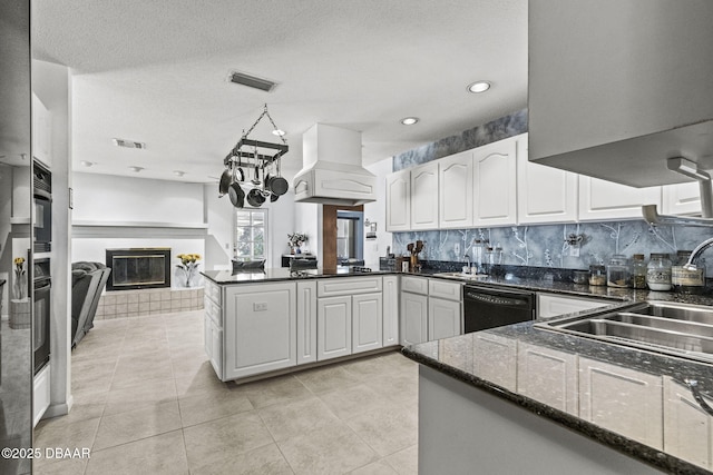 kitchen featuring visible vents, custom exhaust hood, black appliances, and a fireplace