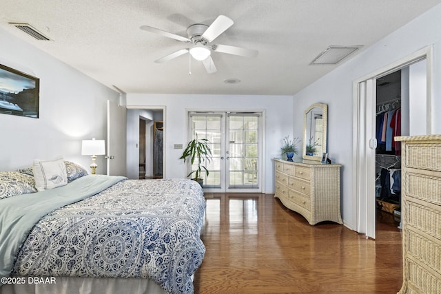 bedroom with a walk in closet, wood finished floors, french doors, and visible vents