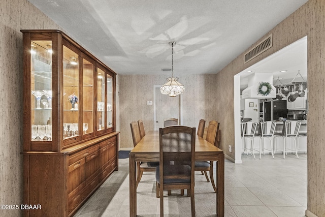 dining room with visible vents, a chandelier, light tile patterned flooring, and wallpapered walls