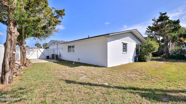 back of house featuring a yard, fence, central AC unit, and a gate