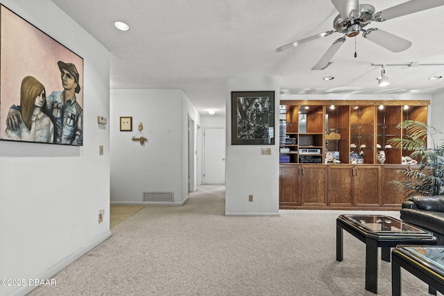 living area featuring a textured ceiling, carpet, visible vents, and baseboards