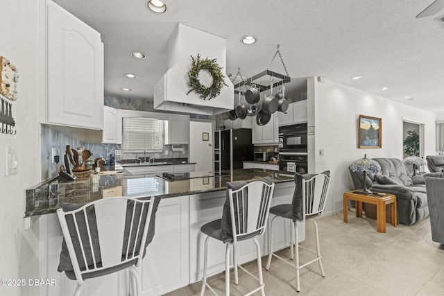 kitchen with black appliances, a sink, open floor plan, recessed lighting, and a peninsula