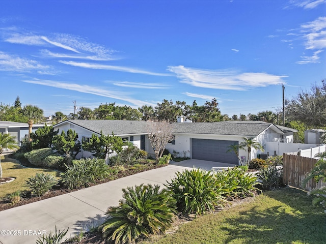 view of front of house featuring fence, a garage, driveway, and stucco siding