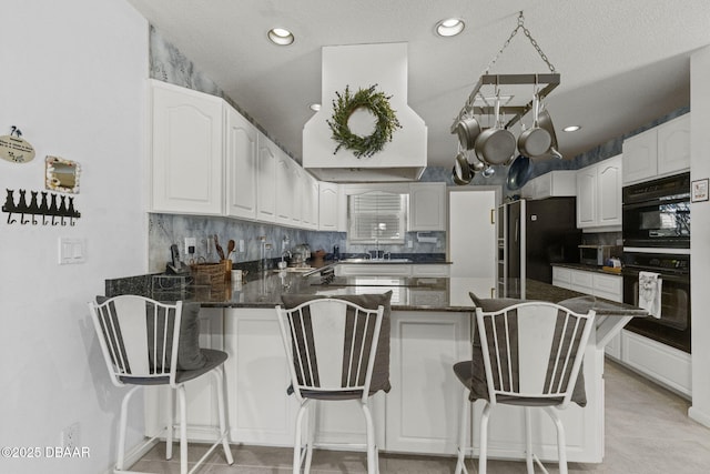 kitchen with decorative backsplash, a peninsula, freestanding refrigerator, and dobule oven black