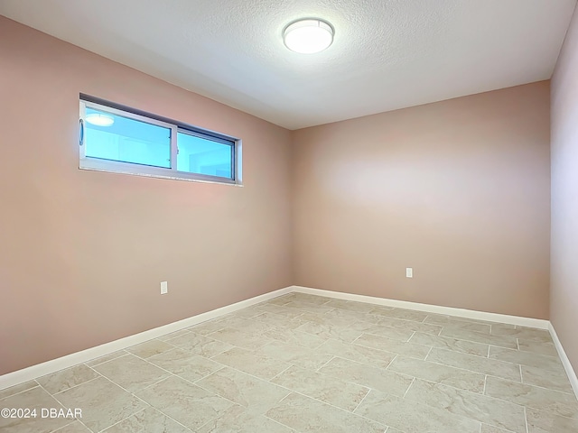 unfurnished room with a textured ceiling